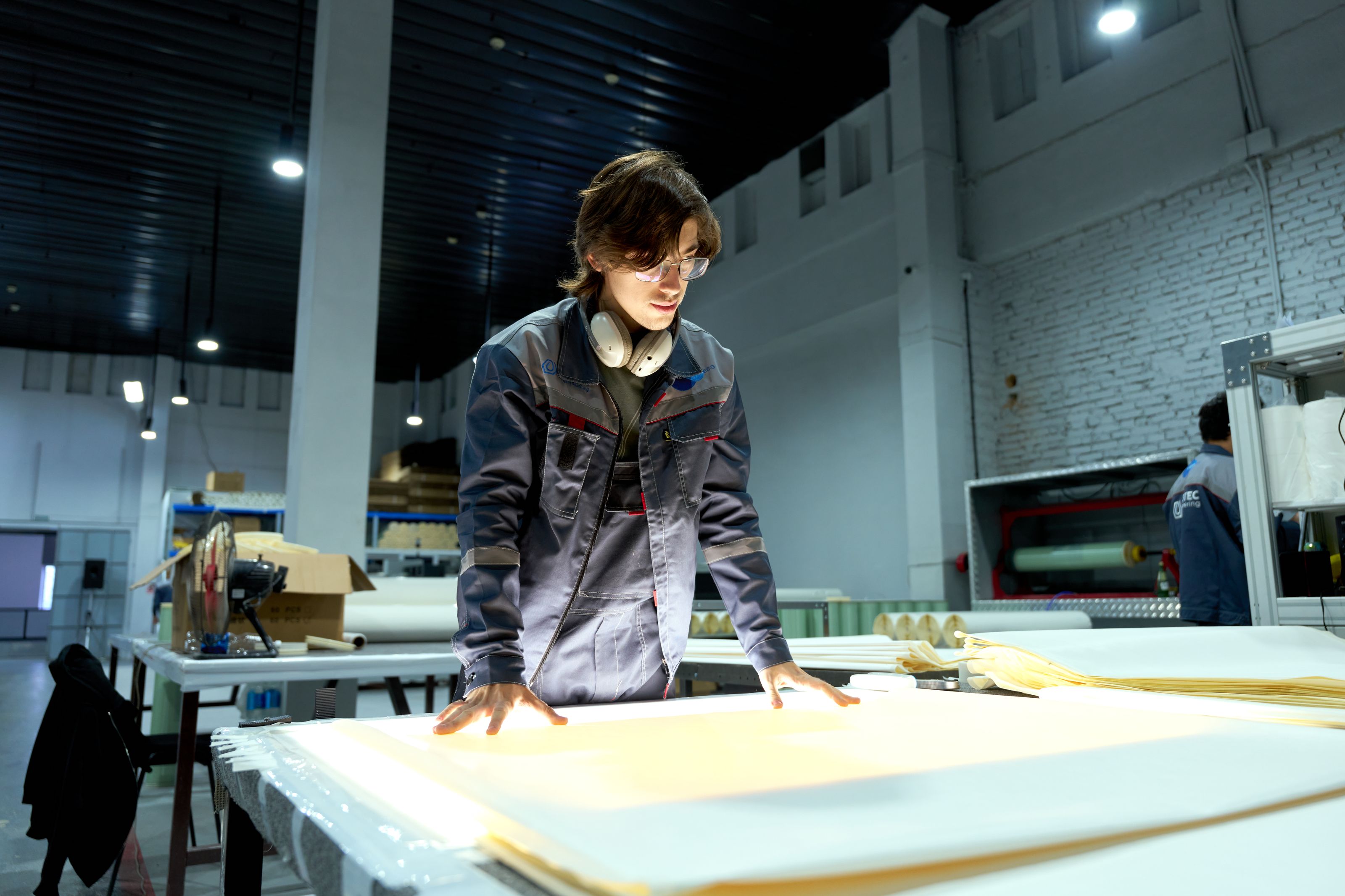 An engineer reviewing designs on a factory floor