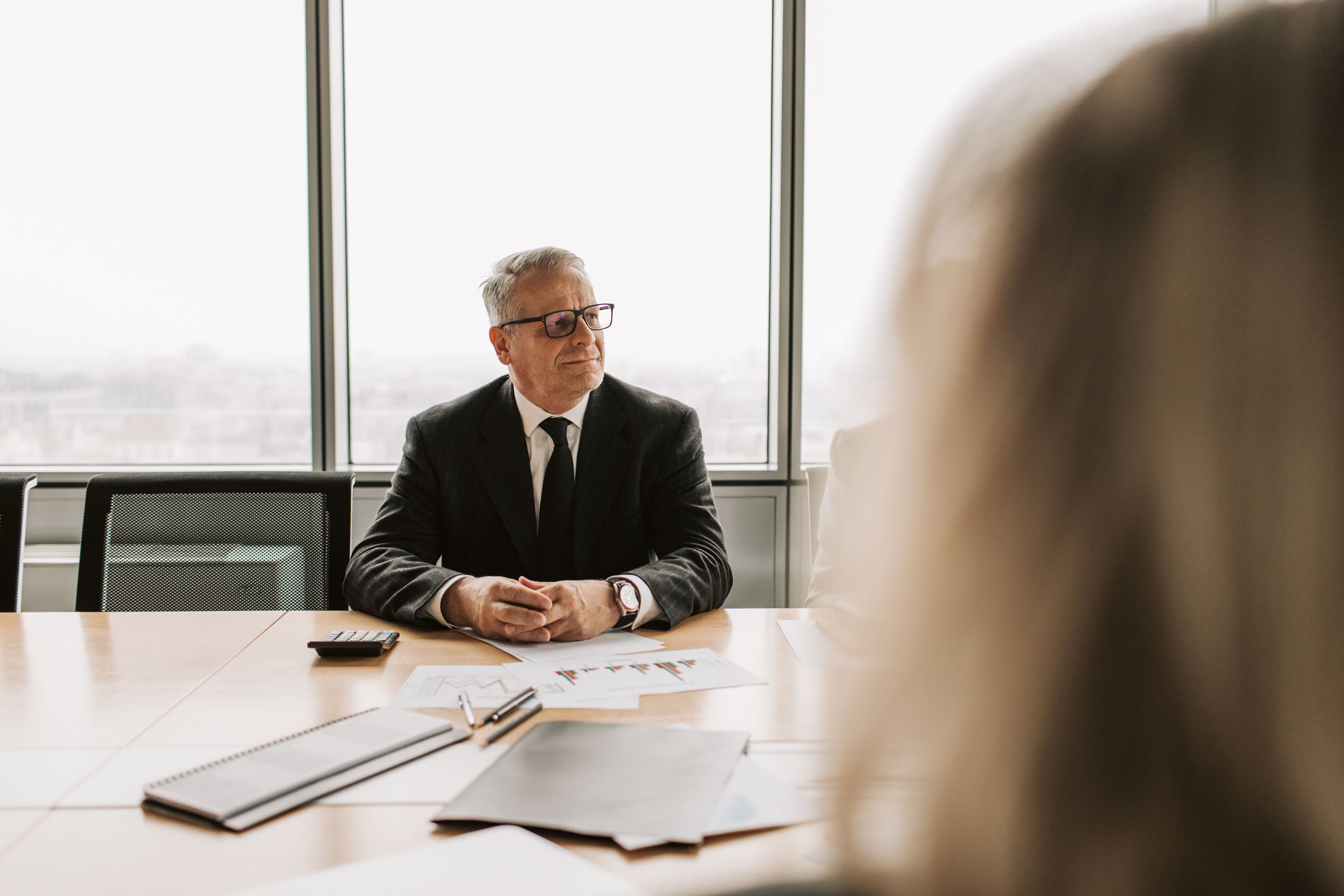 A senior executive at a boardroom table in daylight