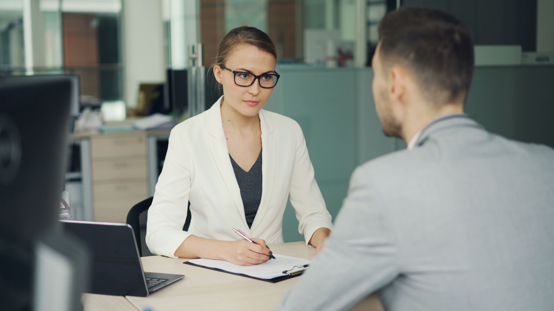 An interview under way across a desk in an open office