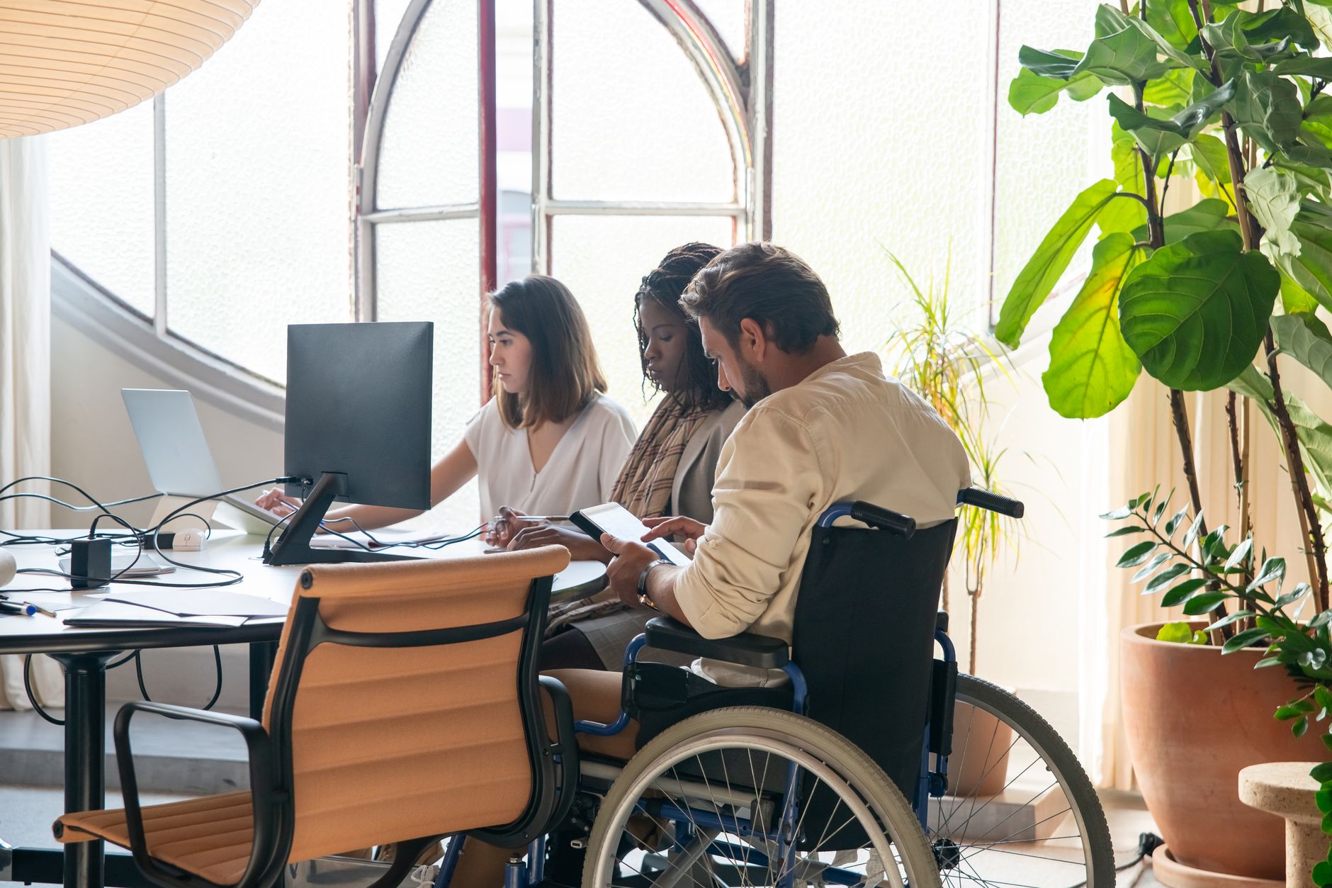 A colleague using a wheelchair working alongside the team at a shared desk