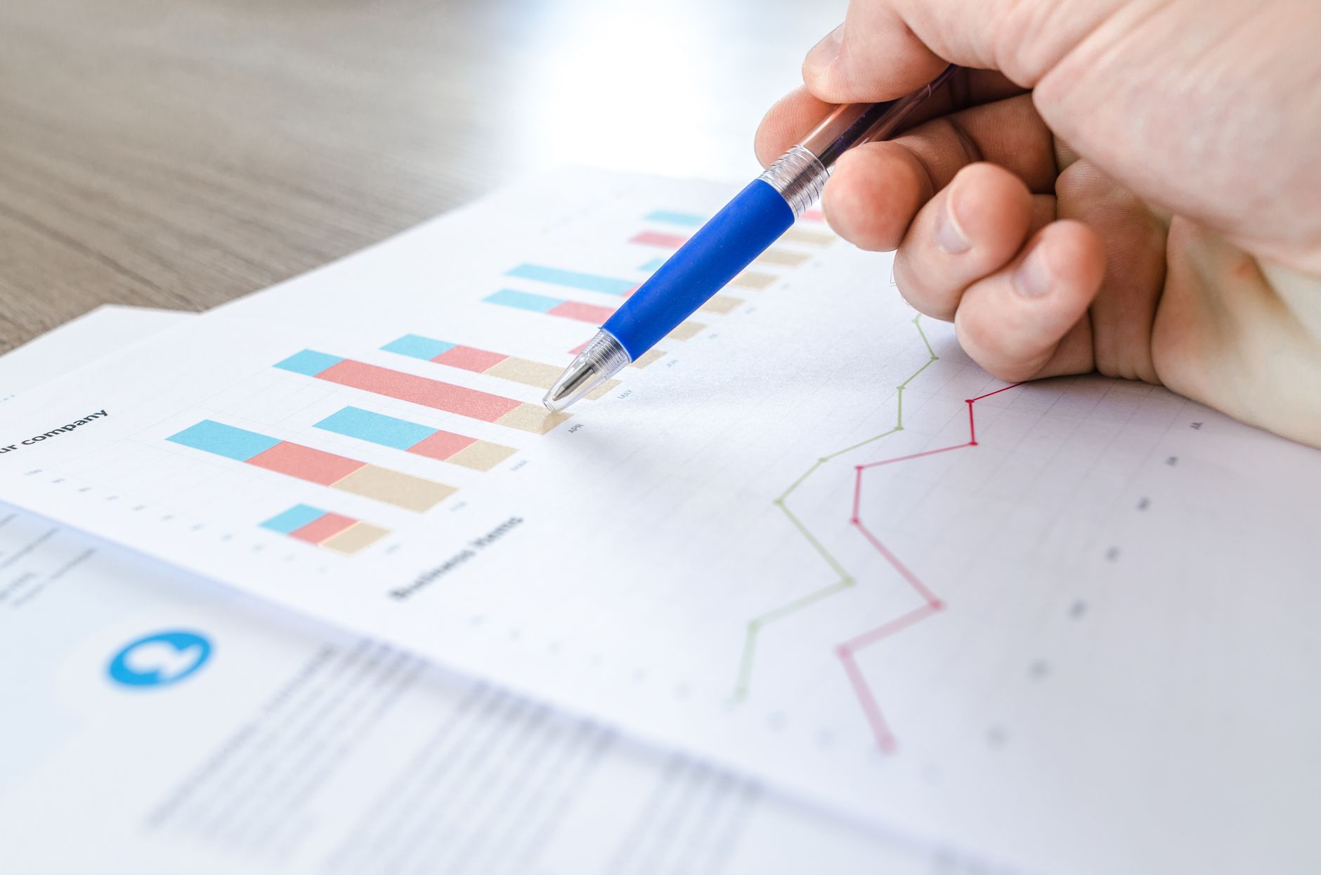 A hand annotating a printed chart of figures