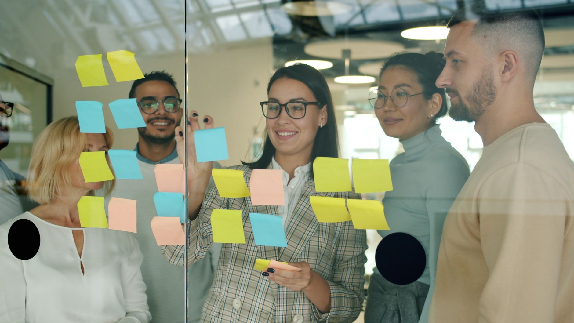 A team mapping work on a glass wall in sticky notes