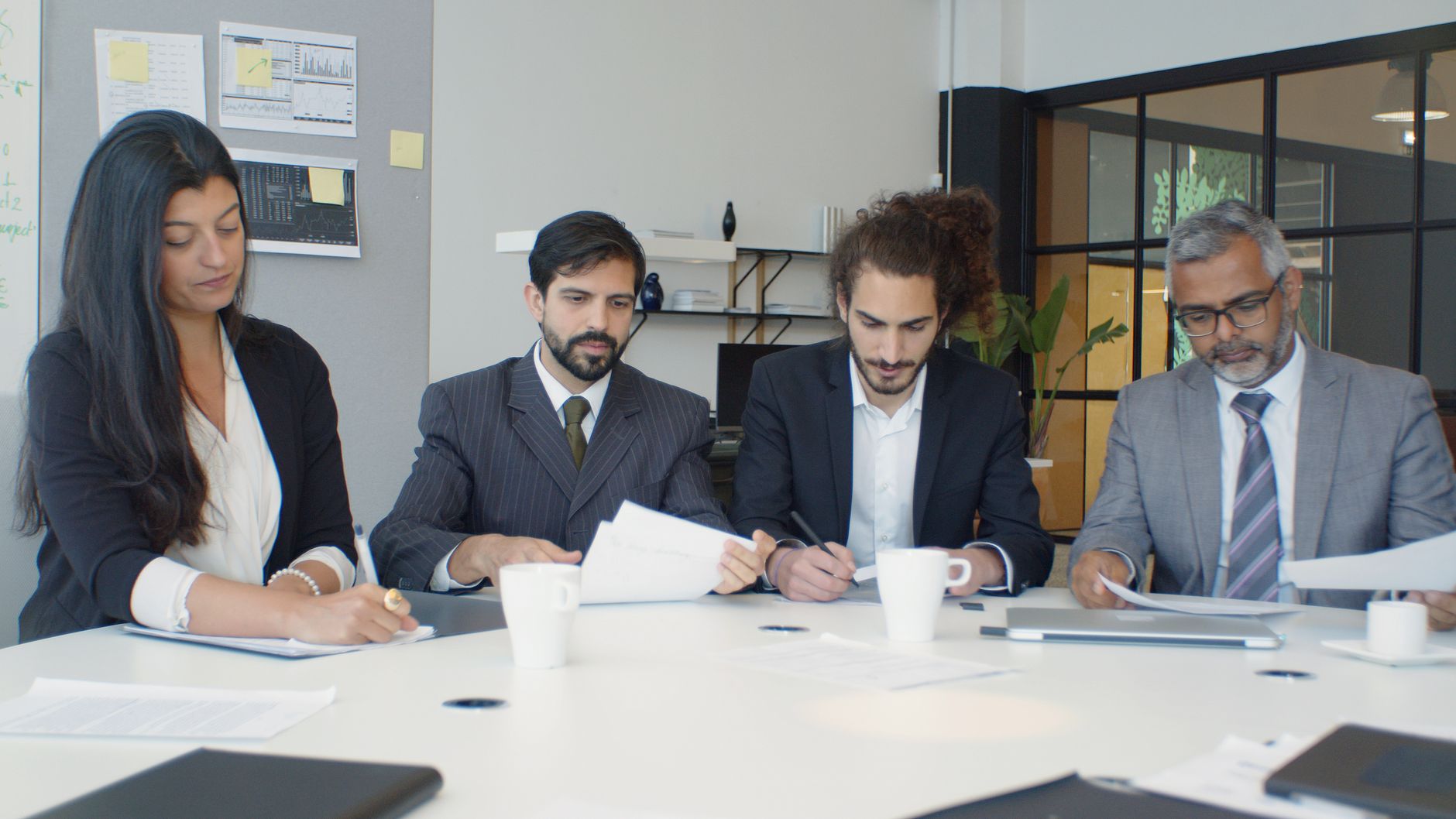 A hiring panel reading candidate papers around a table